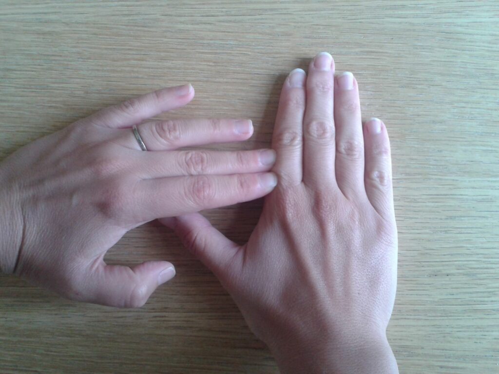 hand palm down, pushing index finger towards thumb