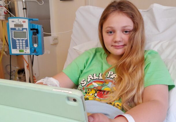 Young girl smiling in hospital bed on ipad