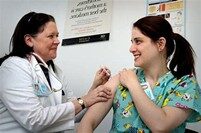female doctor giving an immunisation injection in the arm of a woman.